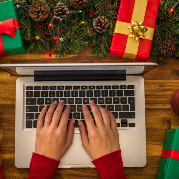 hands typing on a laptop working on accurate accounting and small business bookkeeping with Christms decorations all around.